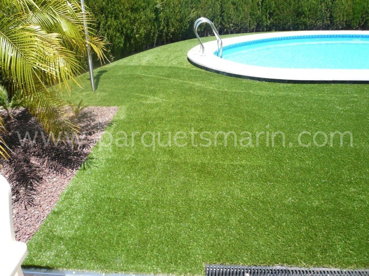 Una piscina está rodeada de un exuberante césped verde.