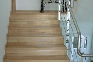 Una escalera de madera con barandilla de acero inoxidable en una casa.