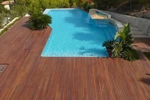 Una gran piscina está rodeada por una terraza de madera.