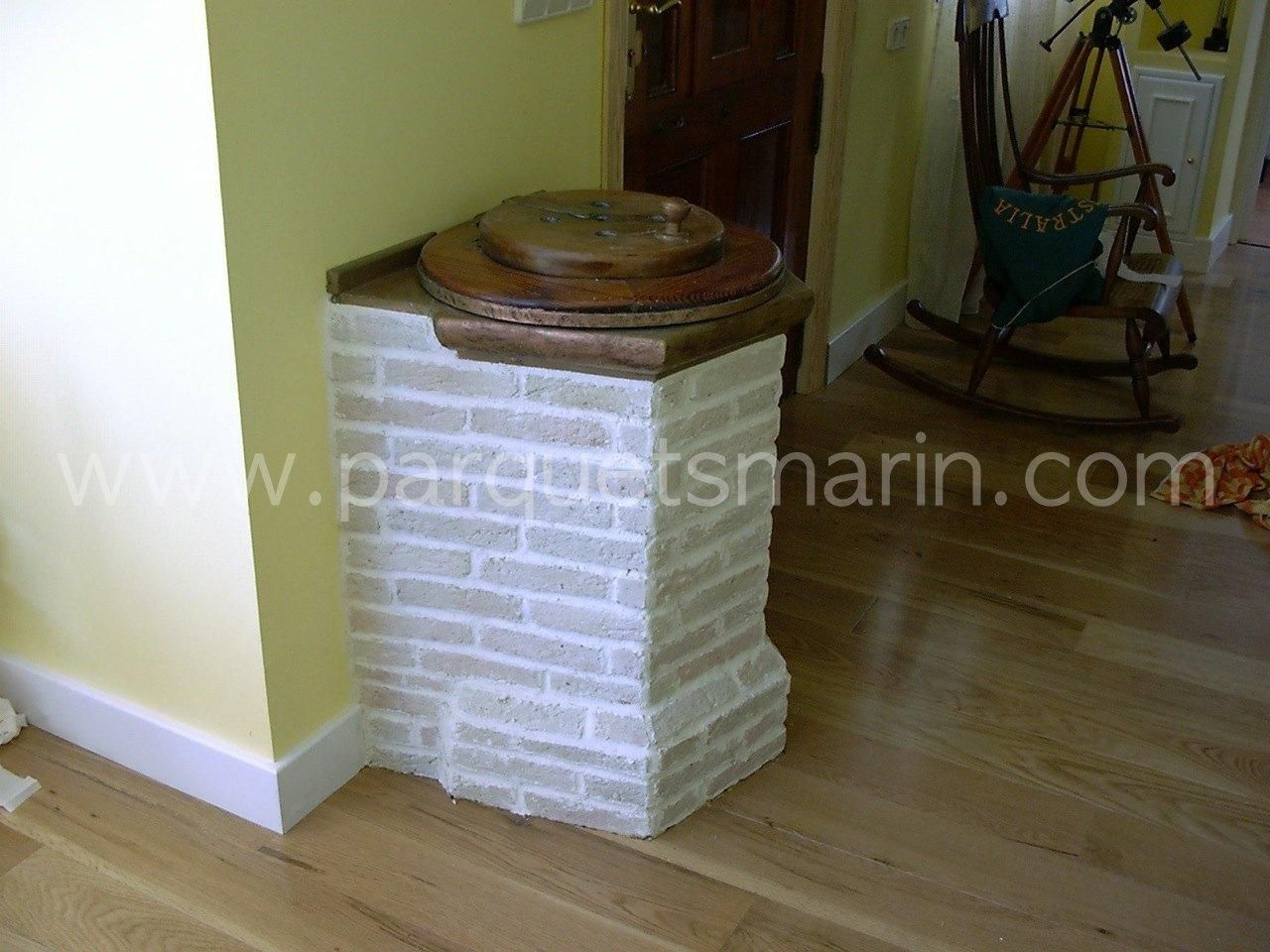 Una mecedora se encuentra junto a un pilar de ladrillo que dice www.parquetsmarin.com