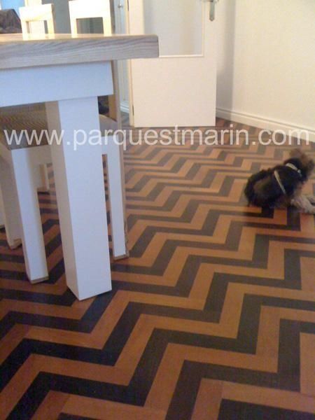 Un perro está parado sobre un piso con estampado de chevrones.