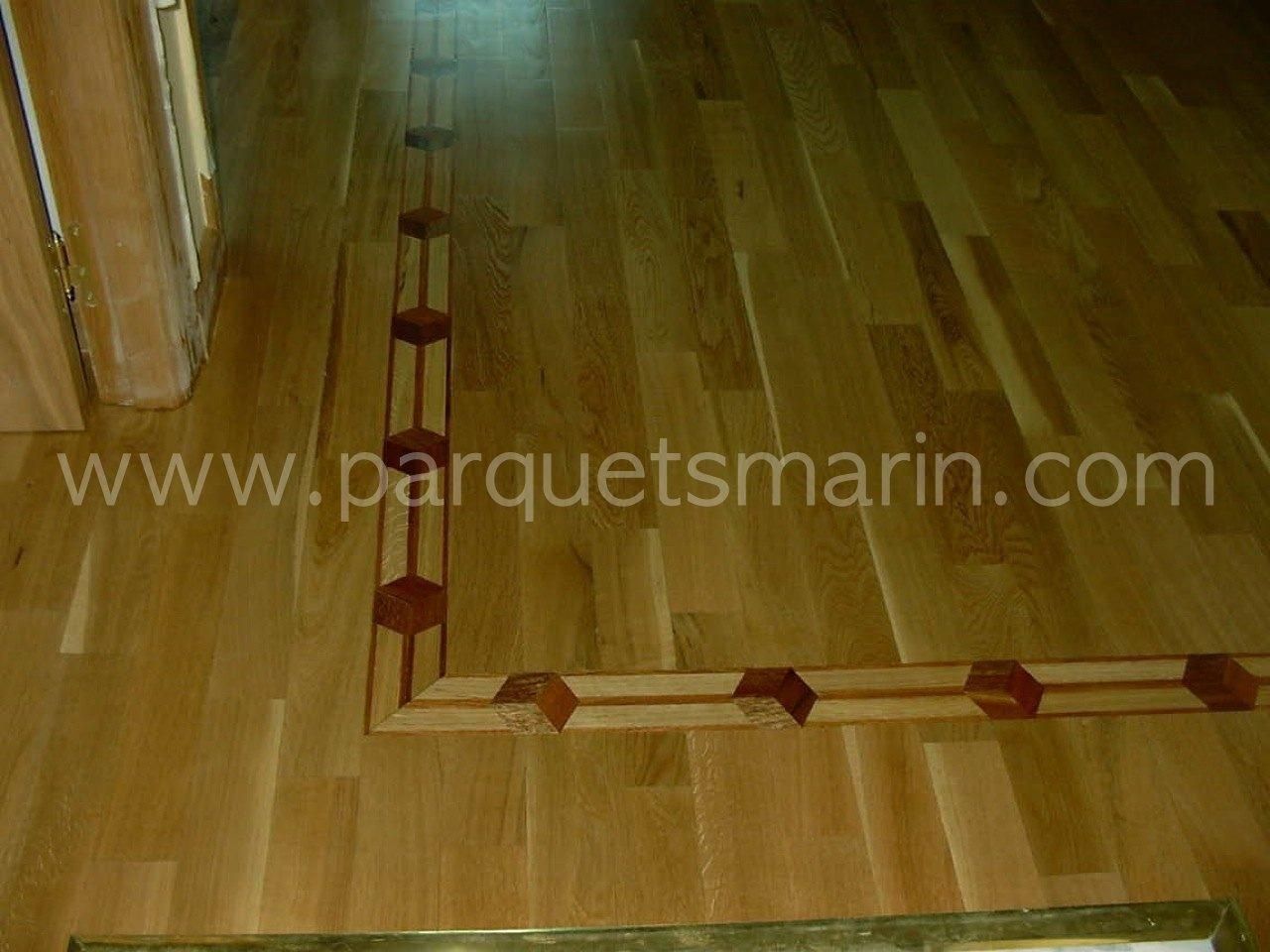 Un suelo de madera con el sitio web www.parquetsmarin.com en la esquina
