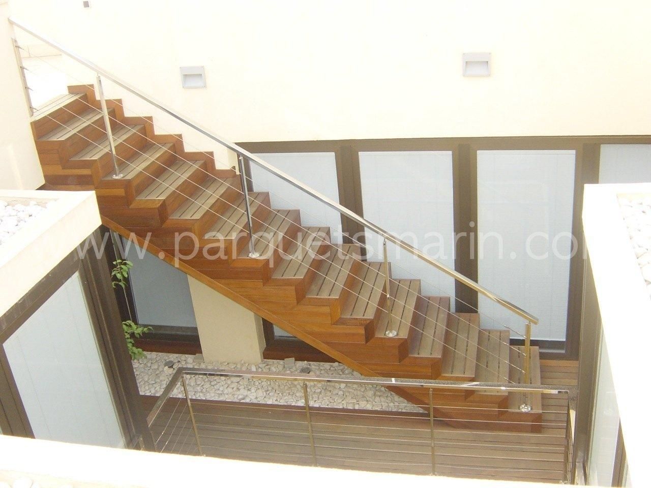 Una escalera de madera con barandilla de acero inoxidable y el sitio web www.parquetmarin.com