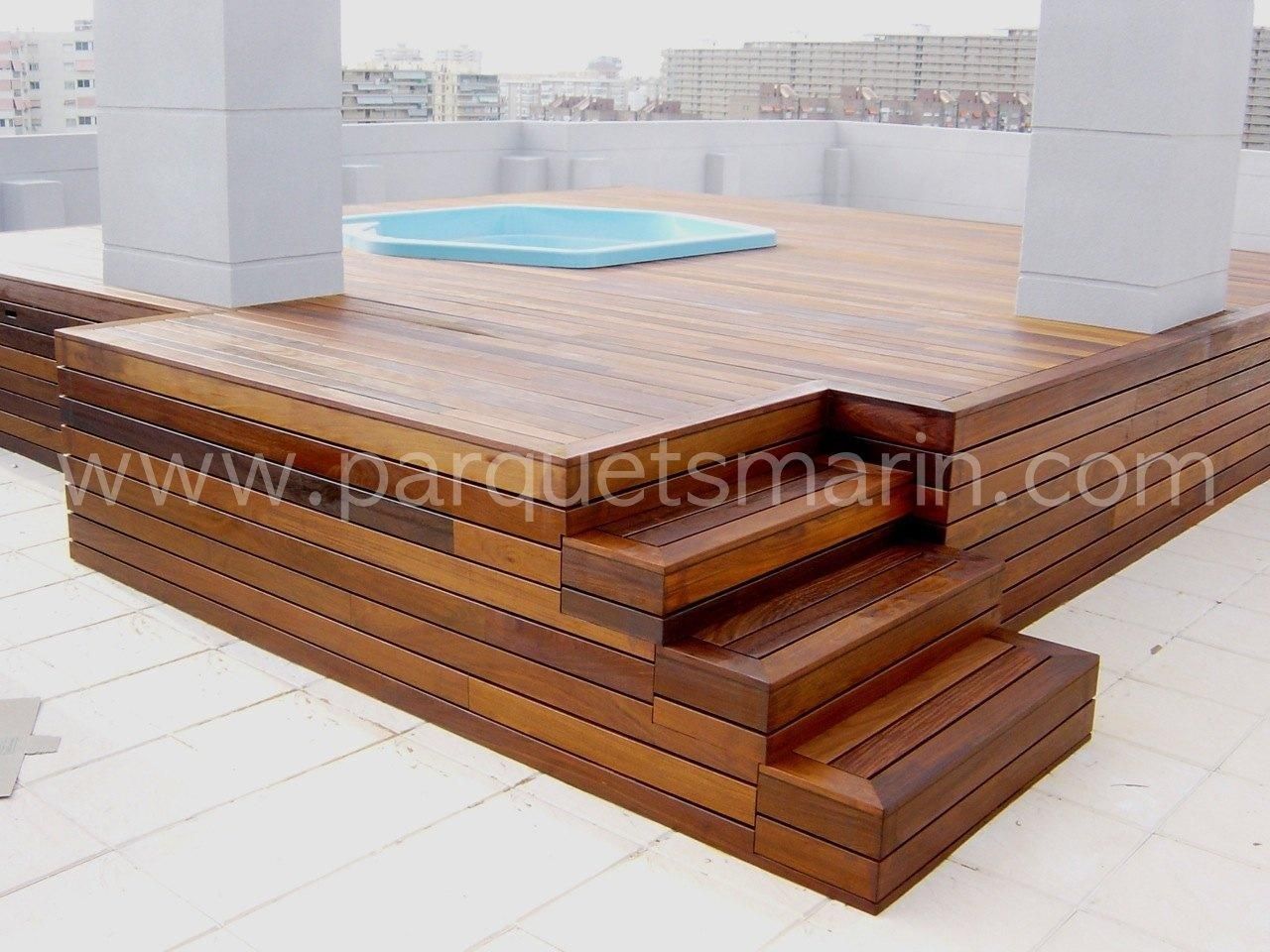 Una terraza de madera con escaleras que conducen a una piscina.