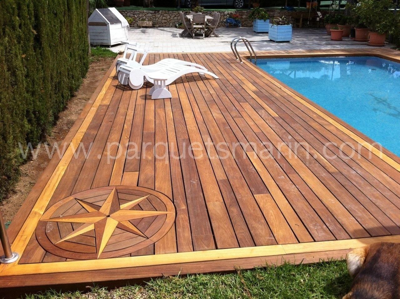 Una terraza de madera junto a una piscina con una brújula en ella.