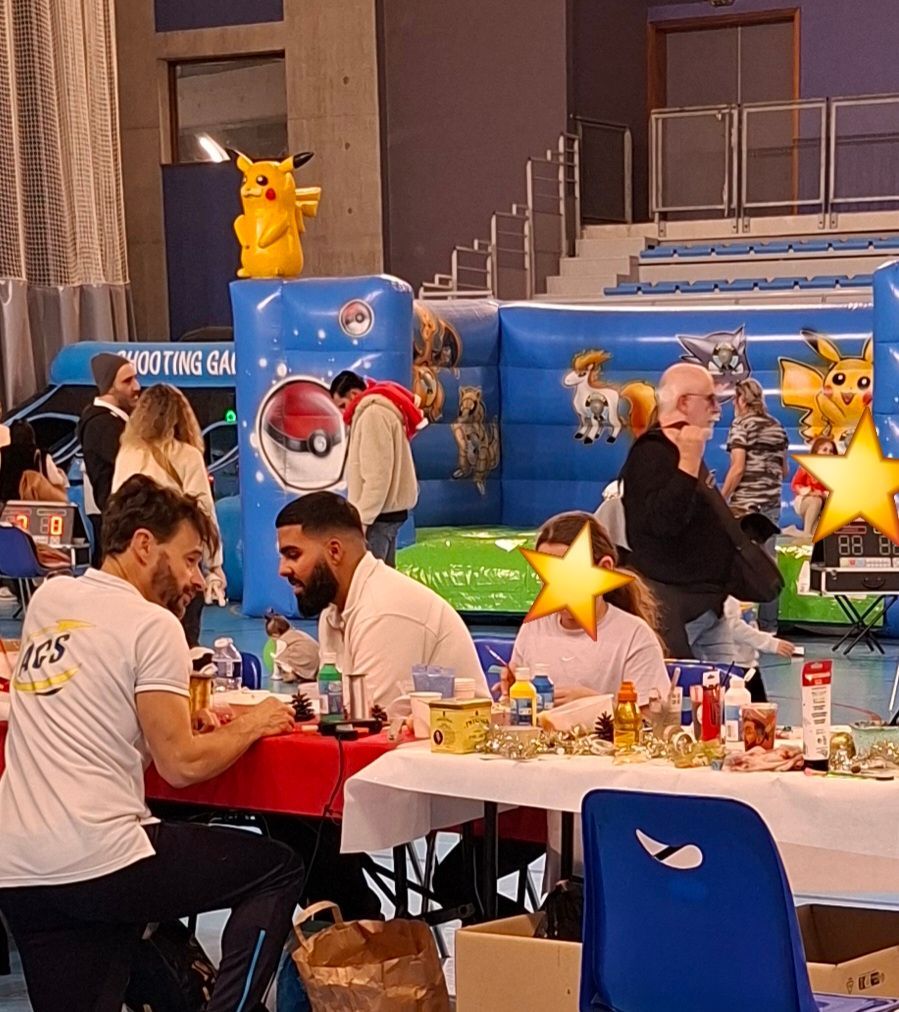 Événement en intérieur avec tables, participants, château gonflable avec des personnages de dessin animé.
