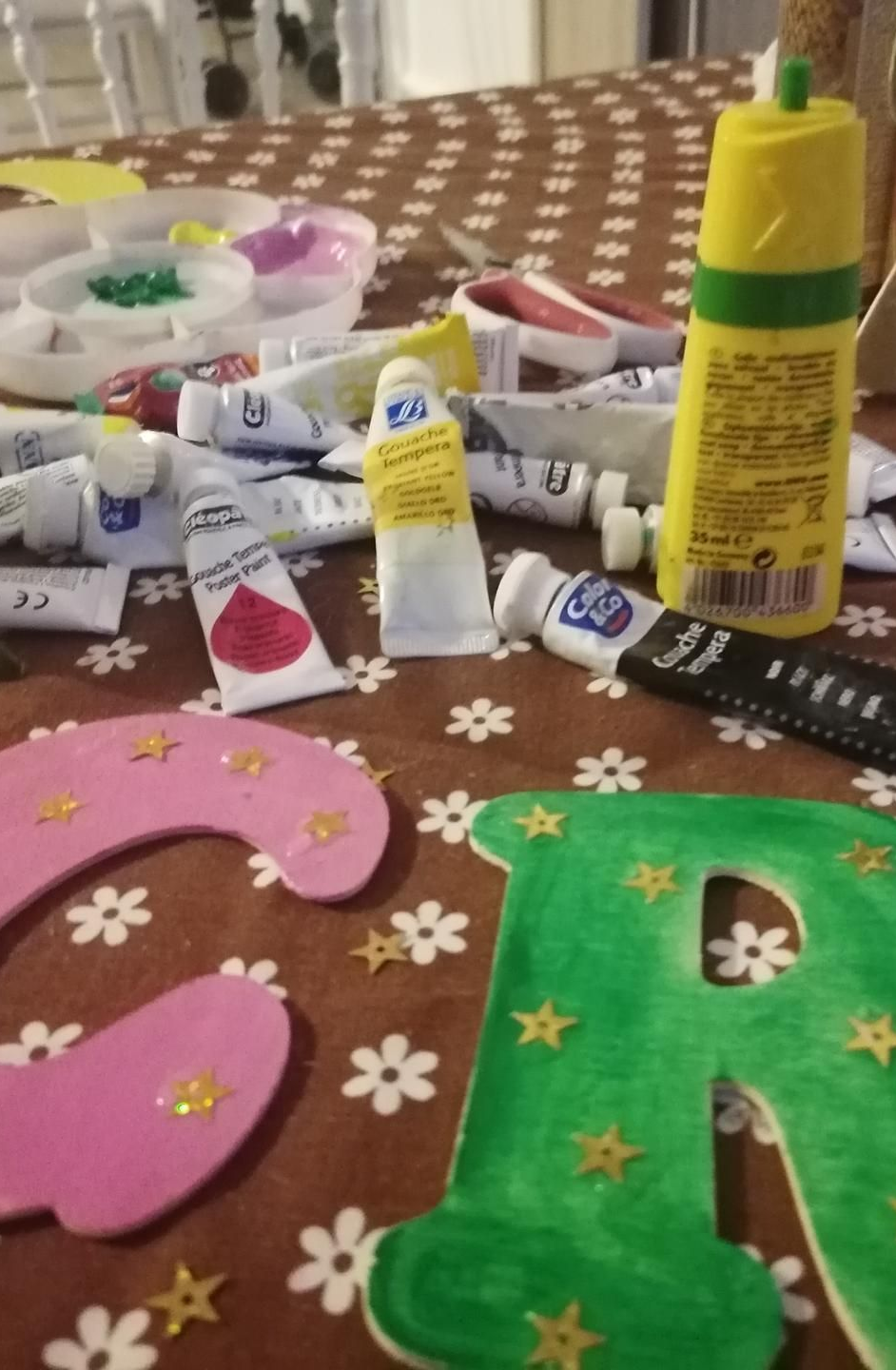 Matériel de loisirs créatifs sur une nappe marron à motifs floraux.