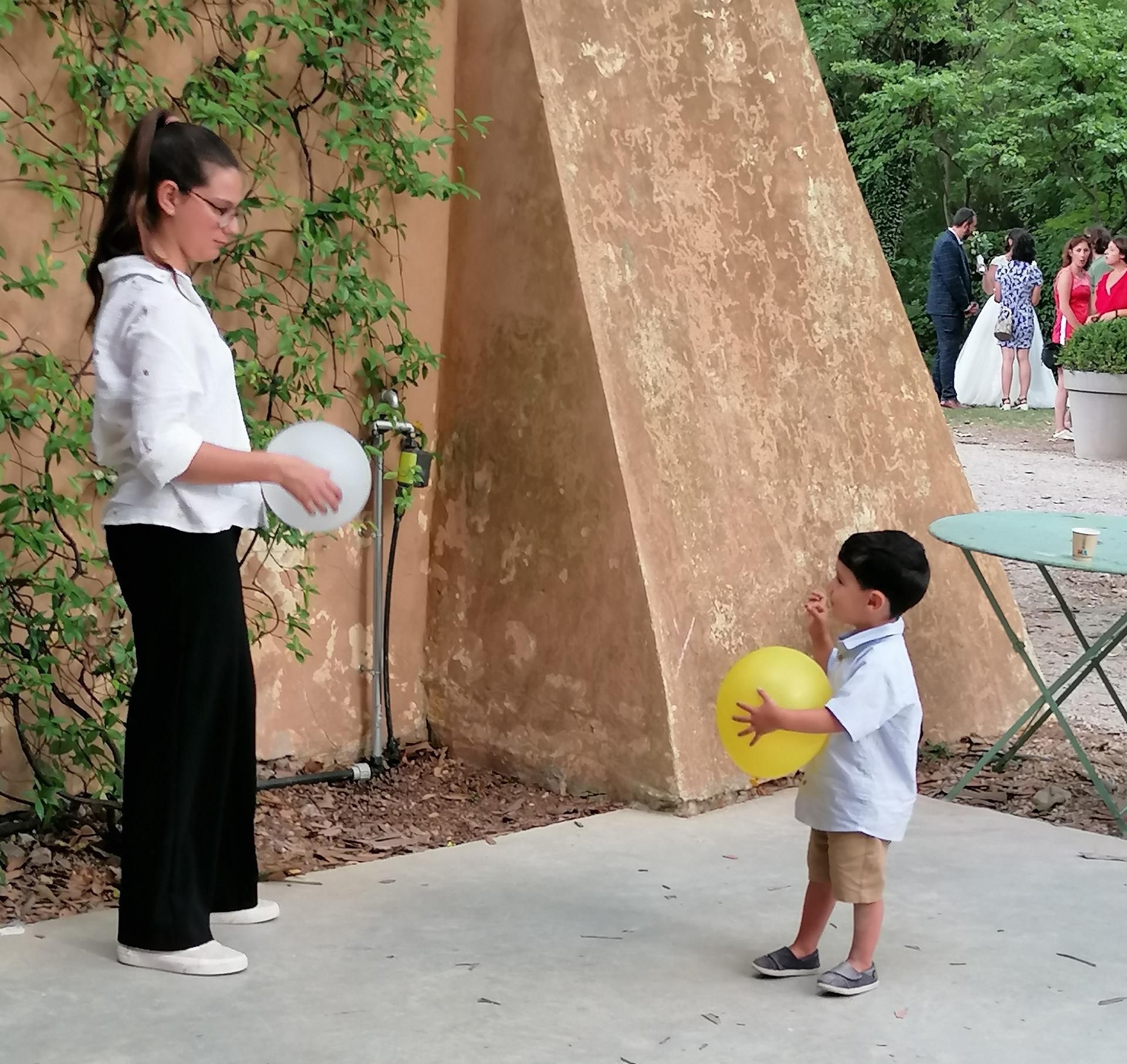 Une femme et un enfant jouent avec des ballons près d'un mur.