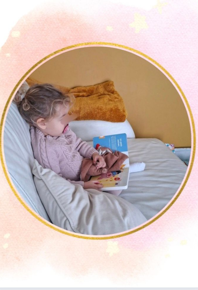 Enfant lisant un livre, allongé sur un lit avec des oreillers. 