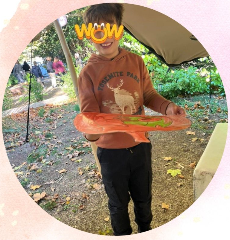 Garçon tenant une œuvre d'art en bois à l'extérieur.