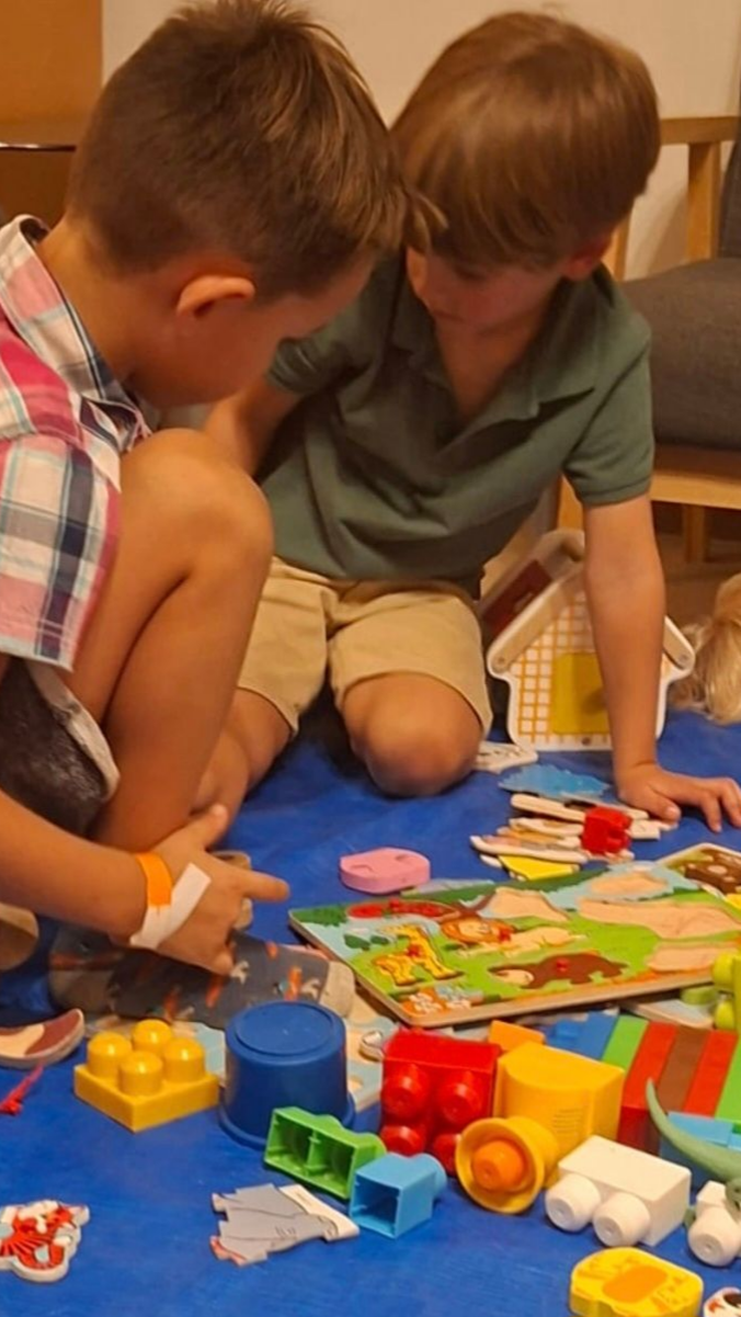 Deux garçons jouent avec des jouets sur un tapis bleu.