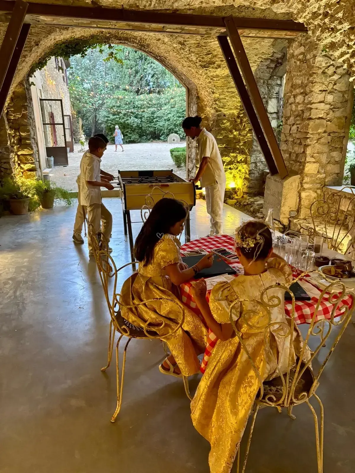 Des enfants jouent à des jeux de société sous des arches de pierre.