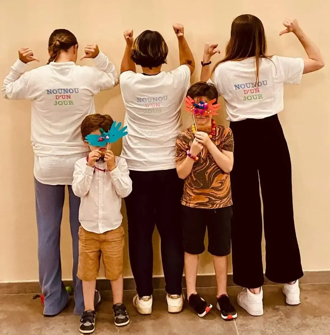 Des personnes et des enfants en chemises blanches, de dos, fléchissent les bras ; deux enfants portent des masques.