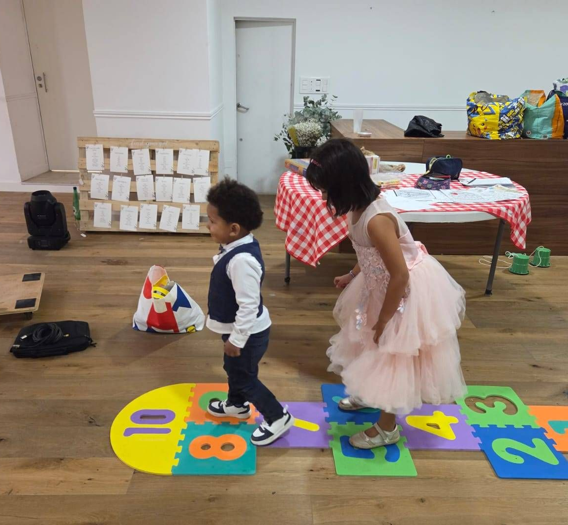 Deux enfants jouent à la marelle à l'intérieur.