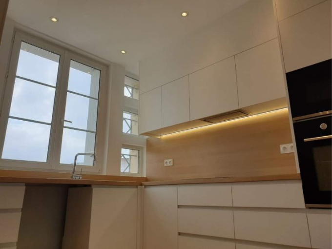 Une cuisine avec des armoires blanches et une fenêtre