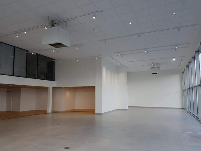 Une grande pièce vide avec beaucoup de fenêtres et un ventilateur de plafond.