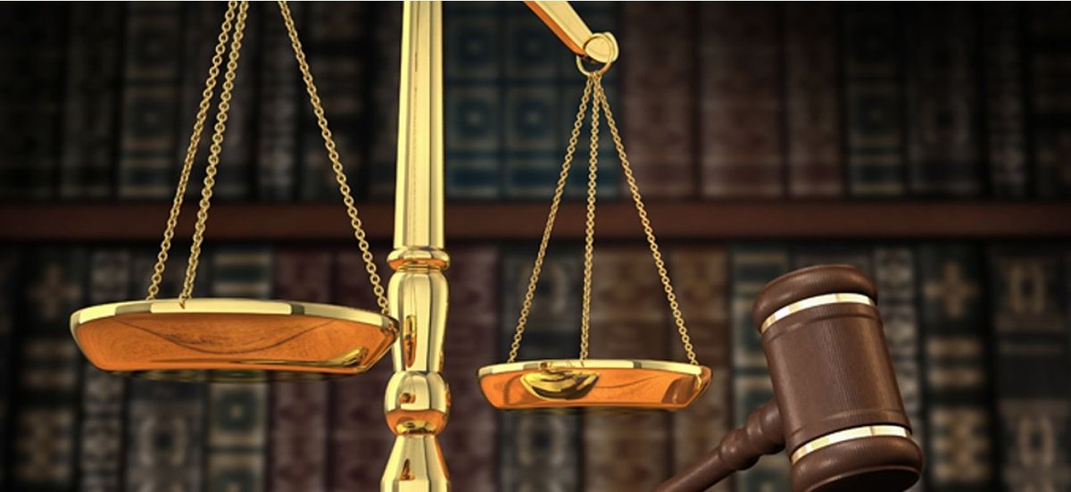 Une balance dorée et un marteau de juge sur une étagère de bibliothèque juridique
