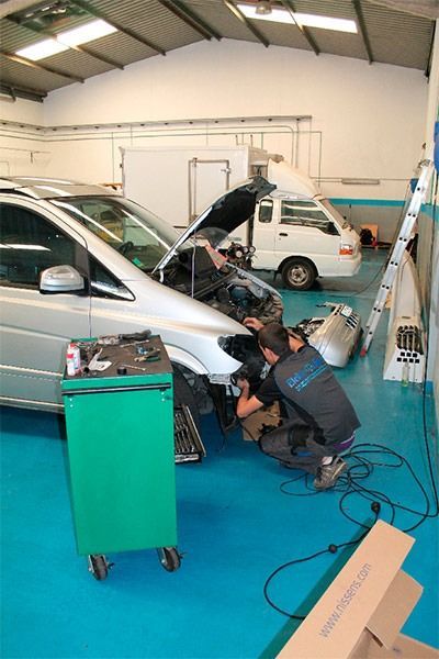 Dos hombres están trabajando en un coche en un garaje.