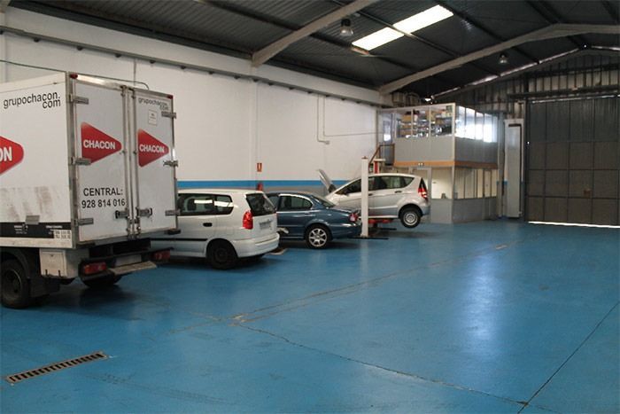 Un almacén con coches y camiones aparcados en él.