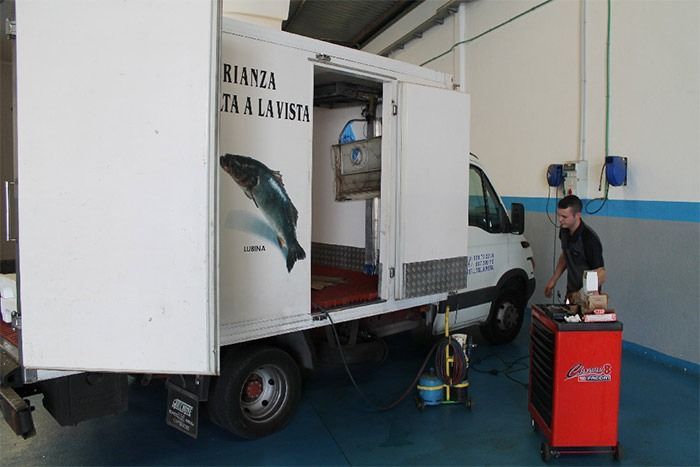 Un hombre está trabajando en un camión en un garaje.