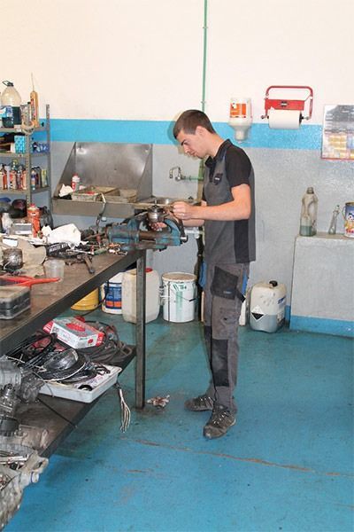 Un hombre está trabajando en una máquina en un garaje.
