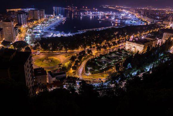 Una vista aérea de una ciudad de noche con un puerto al fondo.