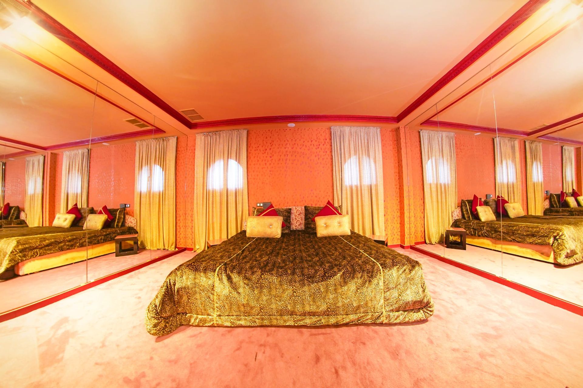 Un dormitorio con una cama grande y muchos espejos.