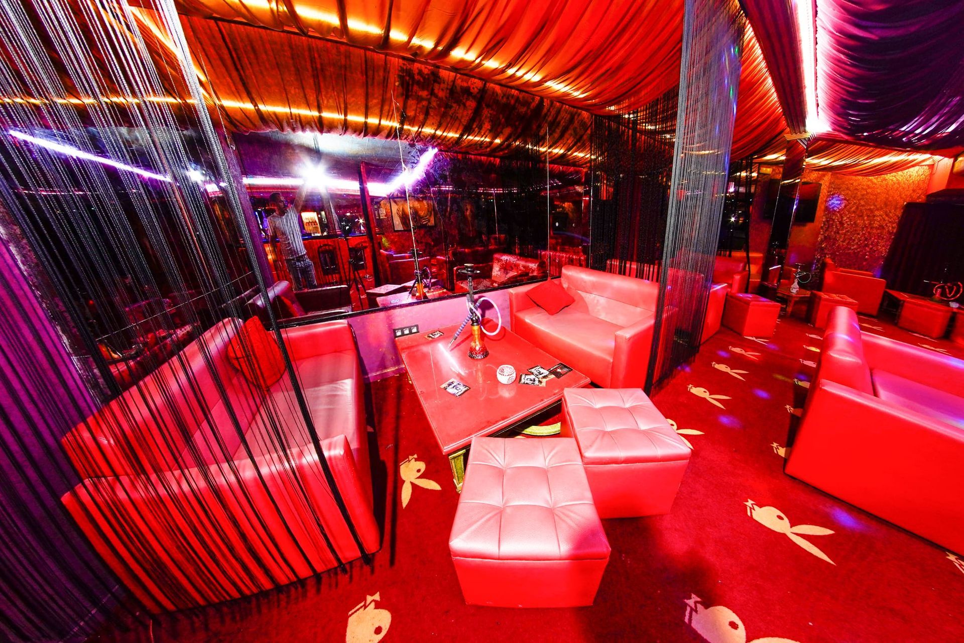 Una habitación con muchos muebles rojos y luces moradas.