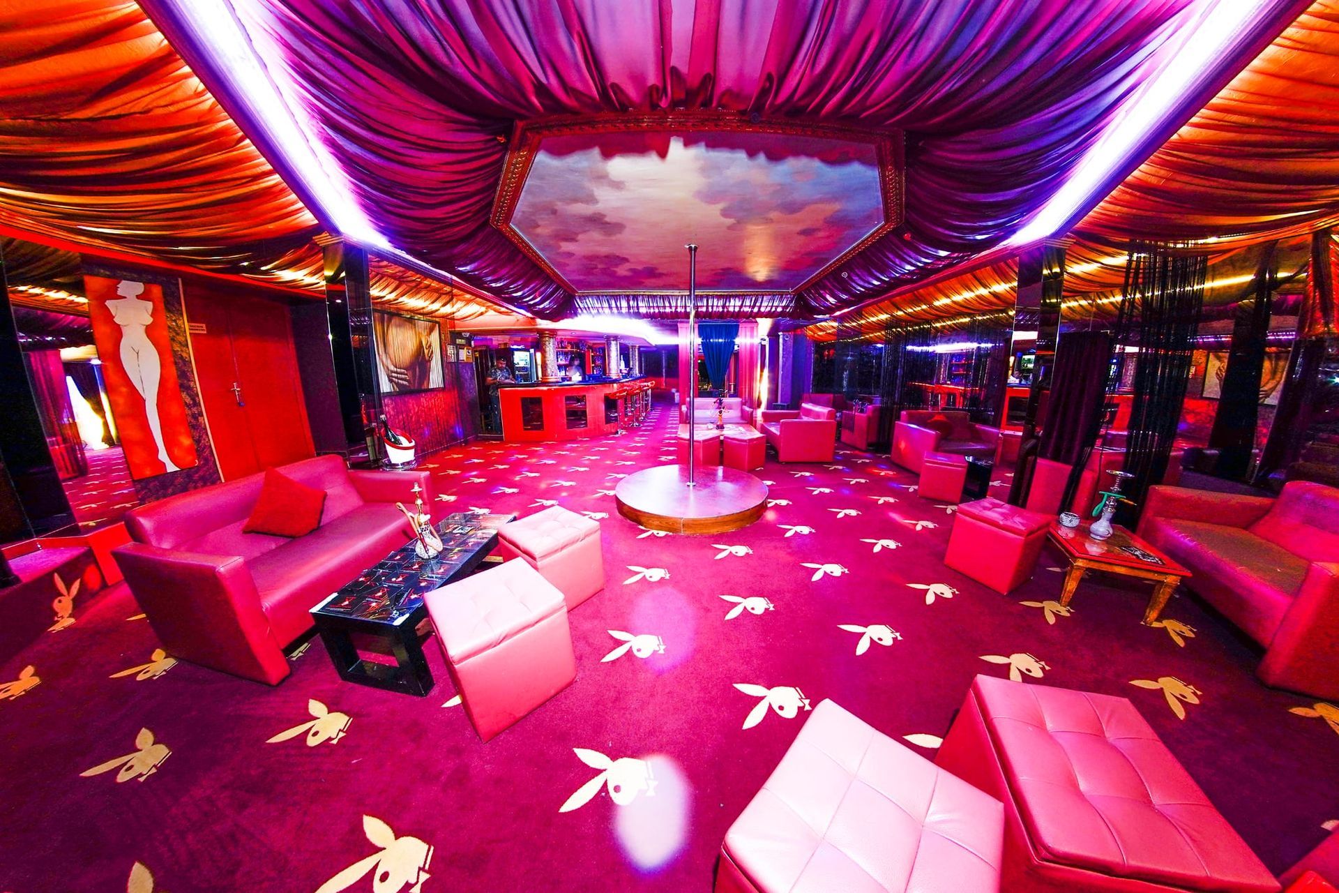 Una habitación grande con muebles rosas y un poste en el medio.