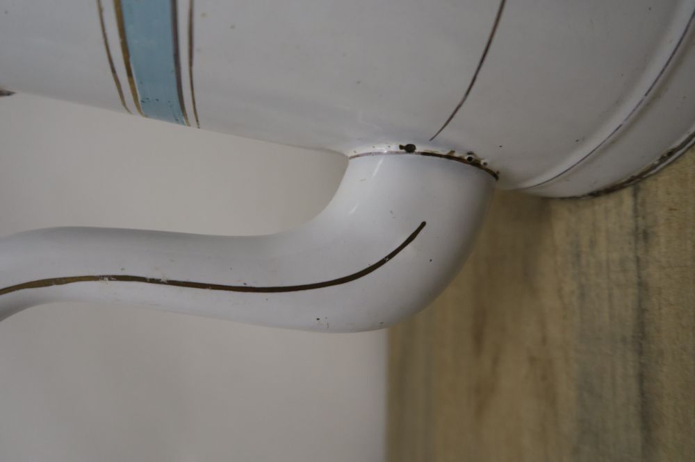 Primer plano del pico de una cafetera de metal blanca de estilo vintage con una fina línea decorativa negra