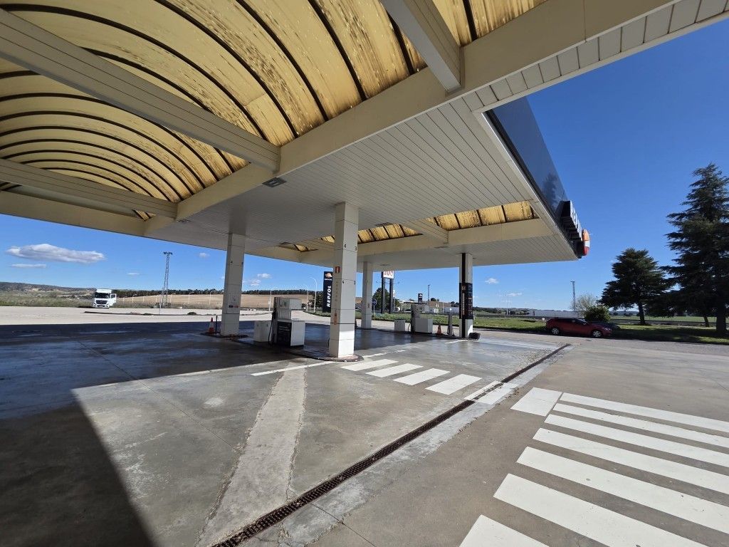 Parada de autobús cubierta con paso de peatones rayado, plataforma de hormigón y cielo azul despejado.