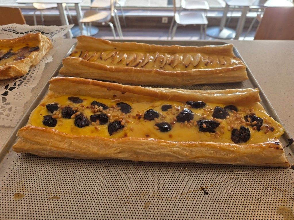 Dos pasteles alargados en una bandeja, uno amarillo con arándanos y otro glaseado simple.