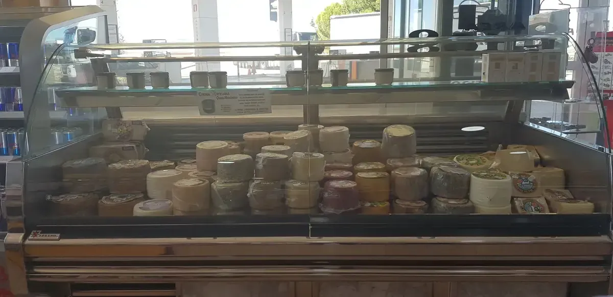 Vitrina de panadería con pasteles y postres variados en bandejas detrás de un cristal.