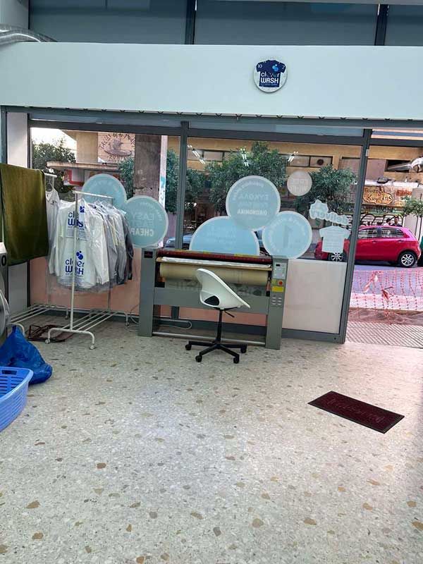 Ένα πλυντήριο με ρούχα κρεμασμένα σε κρεμάστρες και μια καρέκλα.