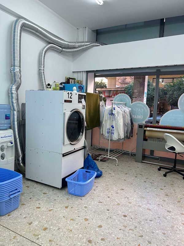 Ένα πλυντήριο ρούχων με πλυντήριο ρούχων και ρούχα κρεμασμένα σε ράφια.