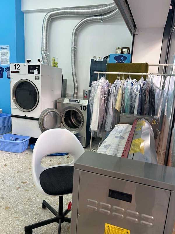 Ένα πλυντήριο ρούχων με πλυντήριο ρούχων, στεγνωτήριο και καρέκλα.