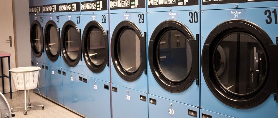 Μια σειρά από μπλε πλυντήρια ρούχων σε ένα πλυντήριο.