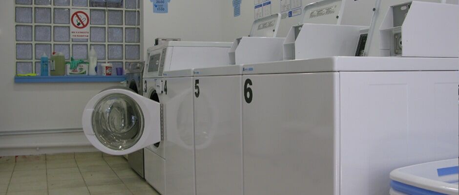 Μια σειρά από πλυντήρια ρούχων σε ένα πλυντήριο με την πόρτα ανοιχτή.