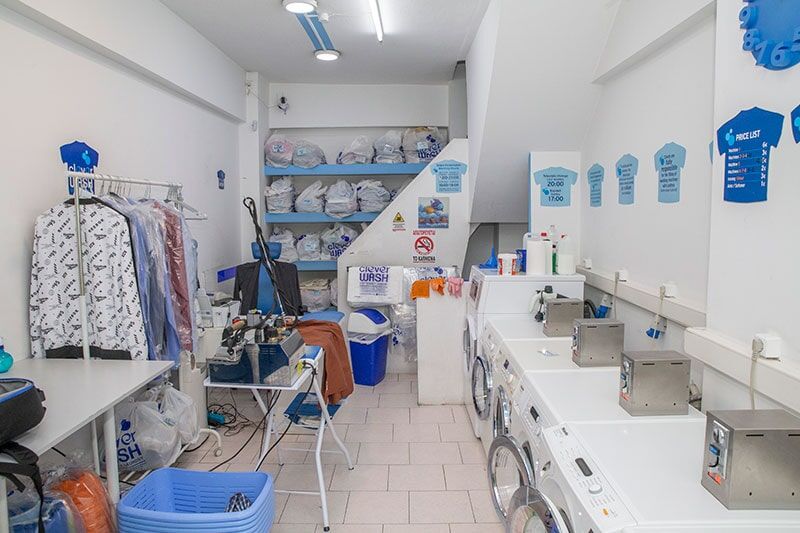 Ένα πλυντήριο ρούχων με μια σειρά από πλυντήρια ρούχων και έναν νεροχύτη.