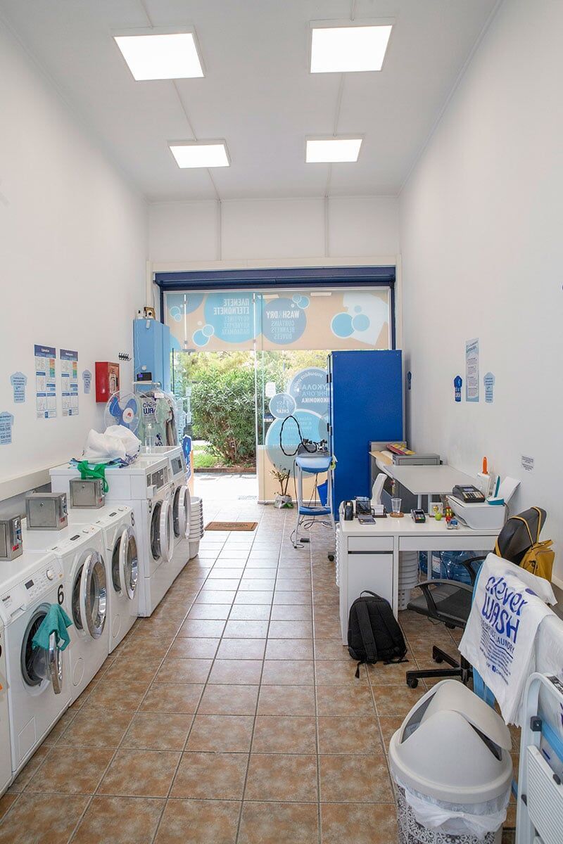 Ένα πλυντήριο με πολλά πλυντήρια ρούχων και ένα γραφείο.