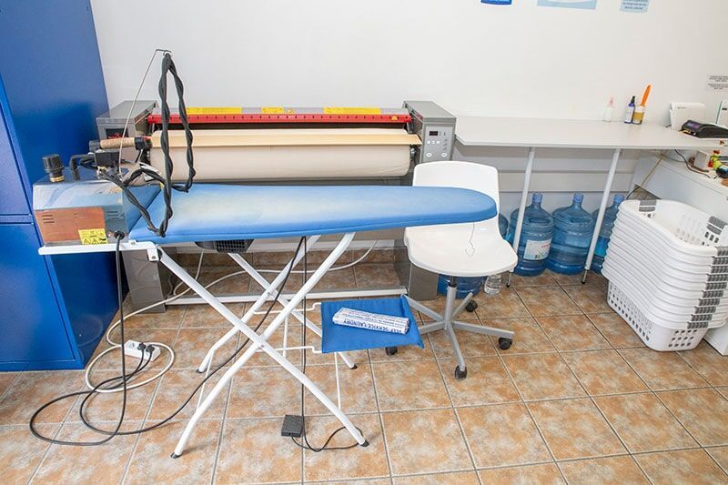 Μια σιδερώστρα βρίσκεται σε ένα δωμάτιο δίπλα σε μια καρέκλα.