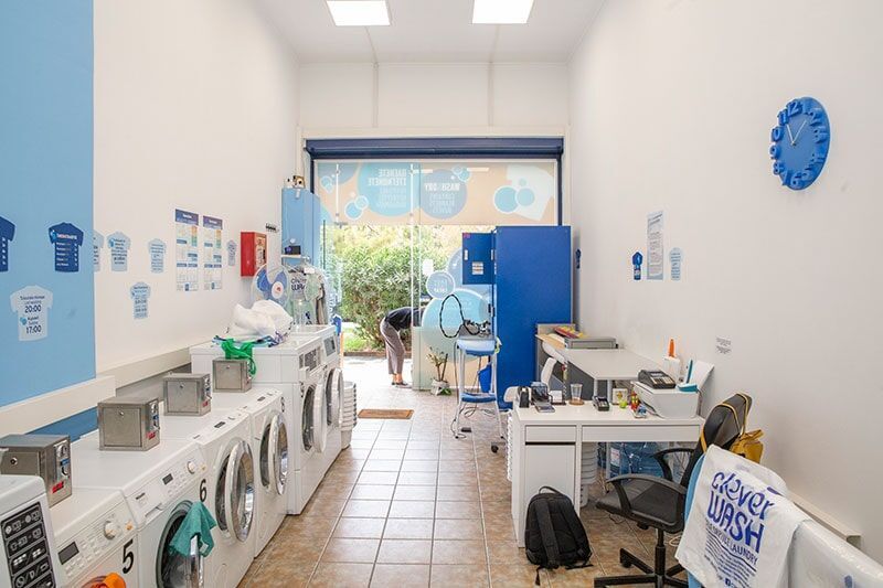 Ένα πλυντήριο με πολλά πλυντήρια ρούχων και ένα γραφείο.