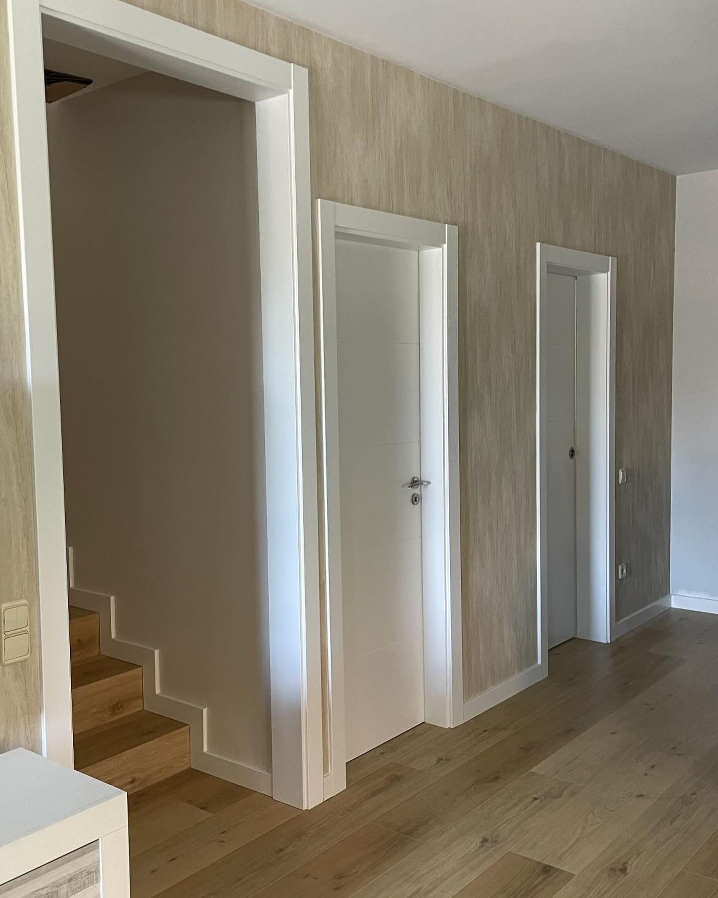 Una cocina con muebles blancos, taburetes, lavavajillas y una ventana.