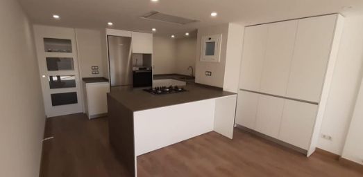 Una cocina con gabinetes blancos, un fregadero, una mesa y sillas.