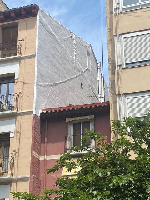 Un edificio con persianas en las ventanas está al lado de otro edificio.