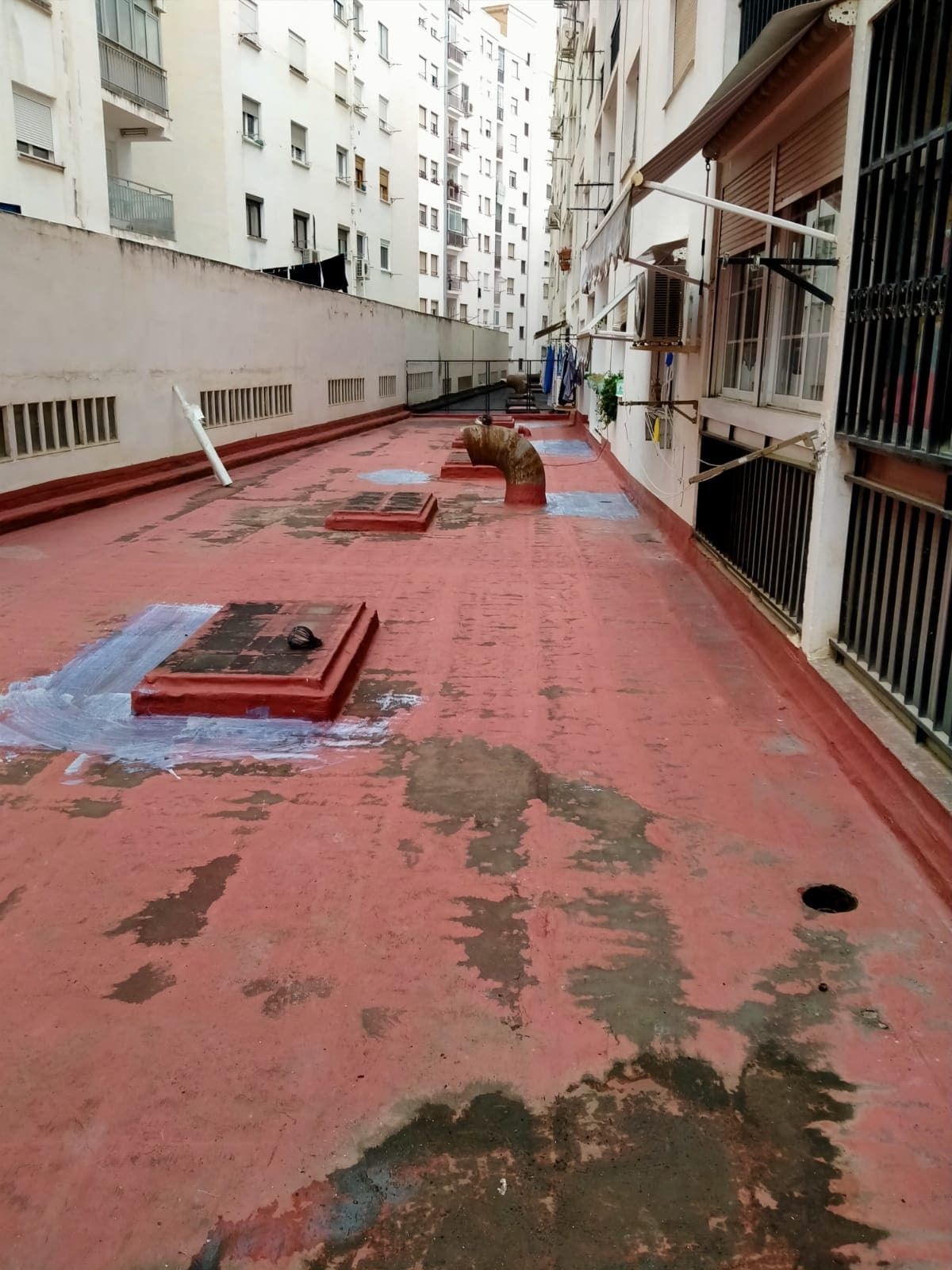 Una pasarela de hormigón rojo entre dos edificios altos.