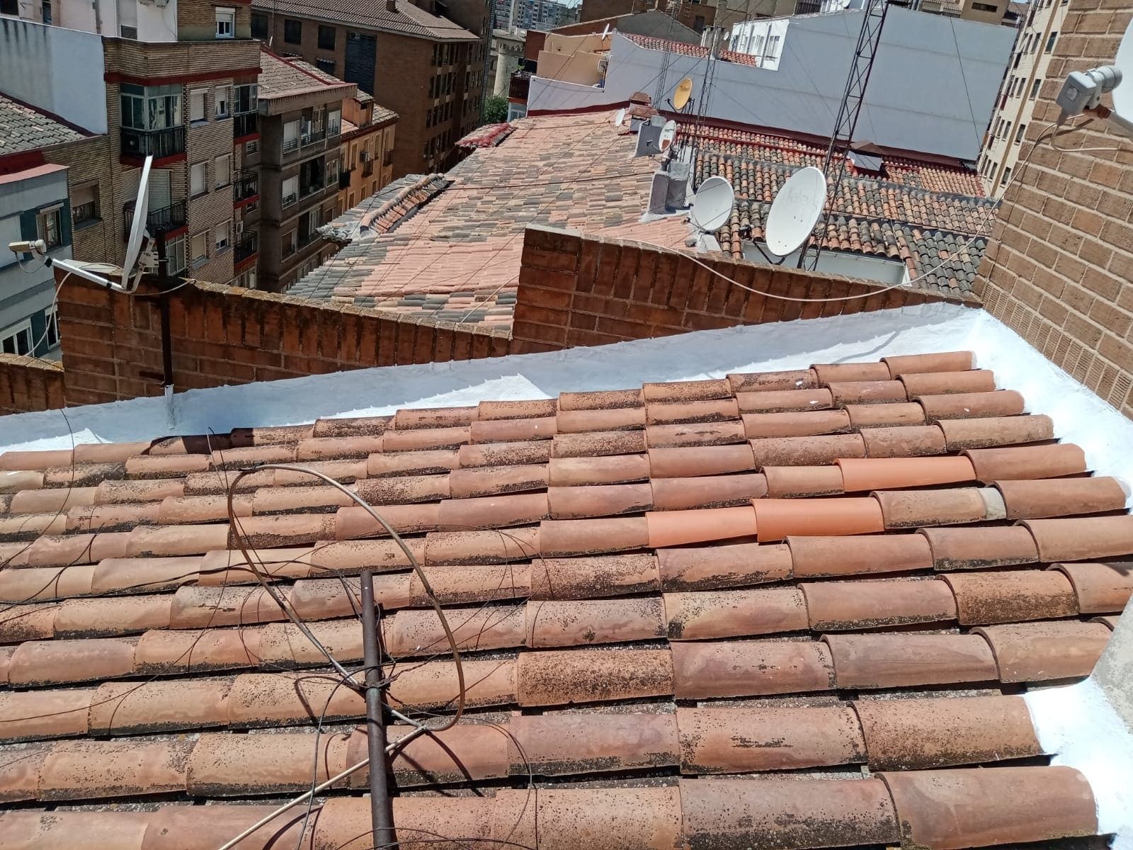 Un techo con muchas tejas y antenas parabólicas.