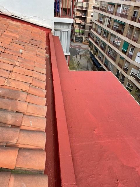 Un techo con tejas rojas y un canalón rojo sobre él.