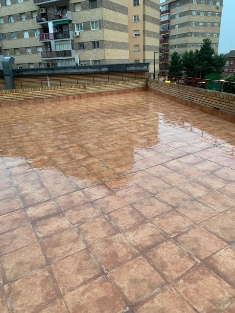 Una terraza en la azotea con azulejos y un edificio al fondo.