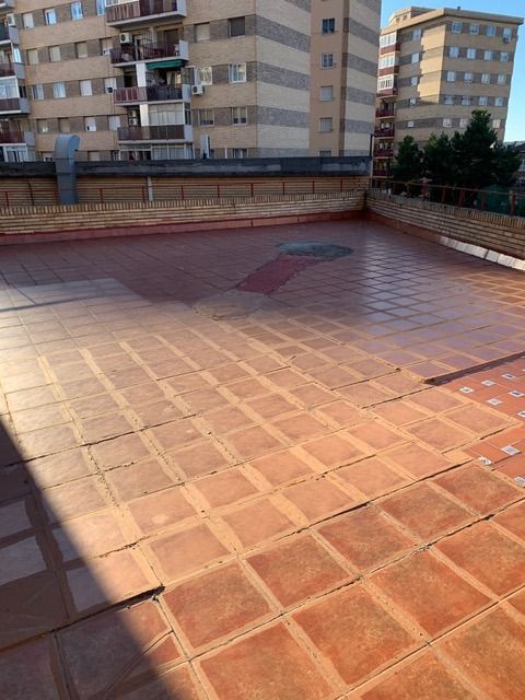 Un suelo de baldosas con un edificio al fondo.